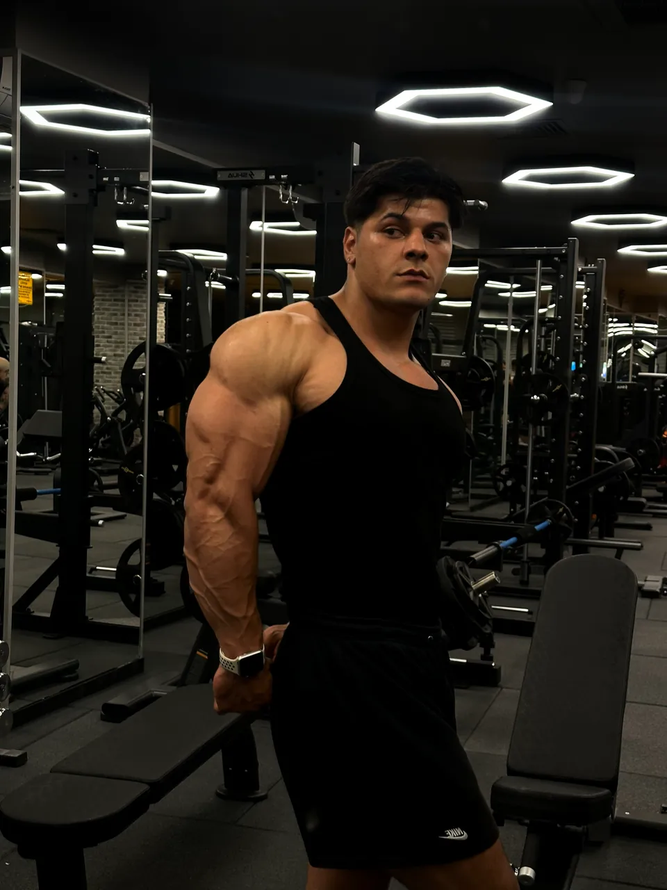 Spor salonunda siyah atletle omzunun üzerinden bakan sporcu.