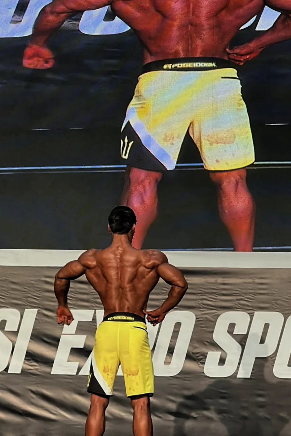 Yarışma sahnesinde arka poz veren sporcu.